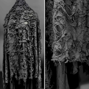 May include: A black, distressed fabric with a ripped and torn texture. The fabric has a rough, uneven surface and appears to be made of a heavy-weight material.