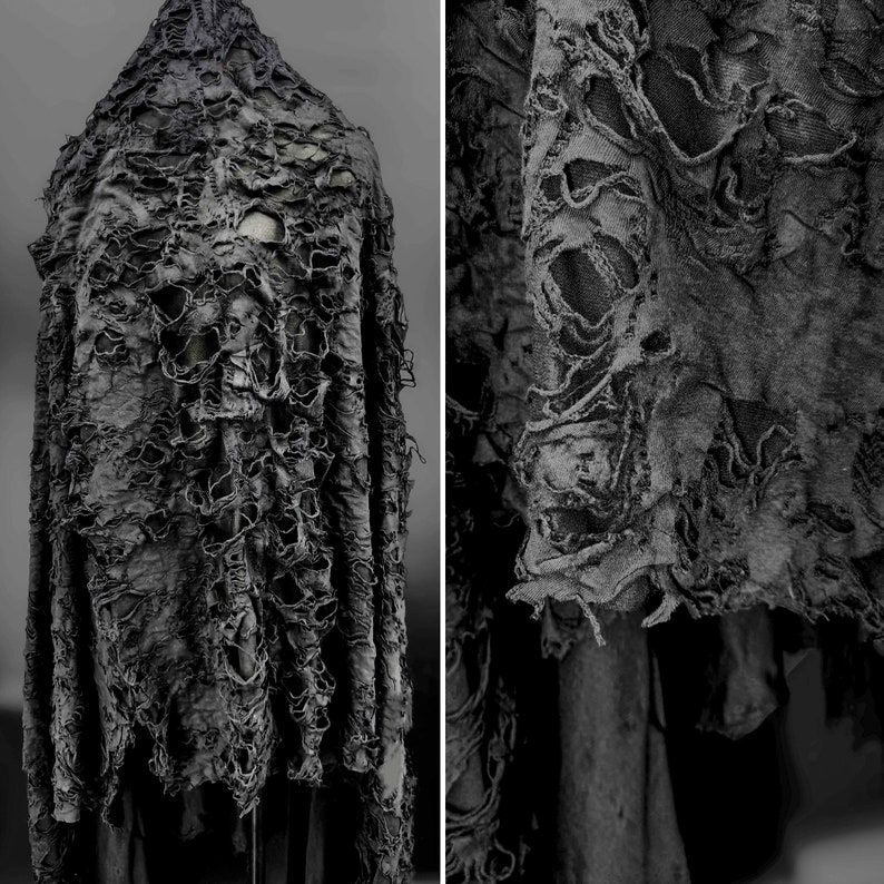 May include: A black, distressed fabric with a ripped and torn texture. The fabric has a rough, uneven surface and appears to be made of a heavy-weight material.