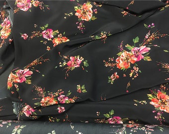 May include: Black fabric with a floral print featuring pink, orange, and green flowers. The fabric is soft and flowing, making it ideal for dresses, skirts, and blouses.