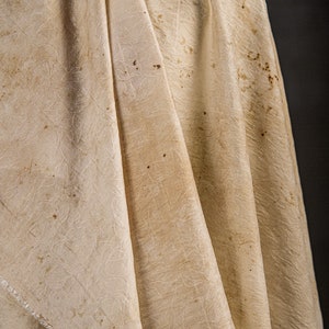 May include: A white fabric with a textured pattern and brown stains.