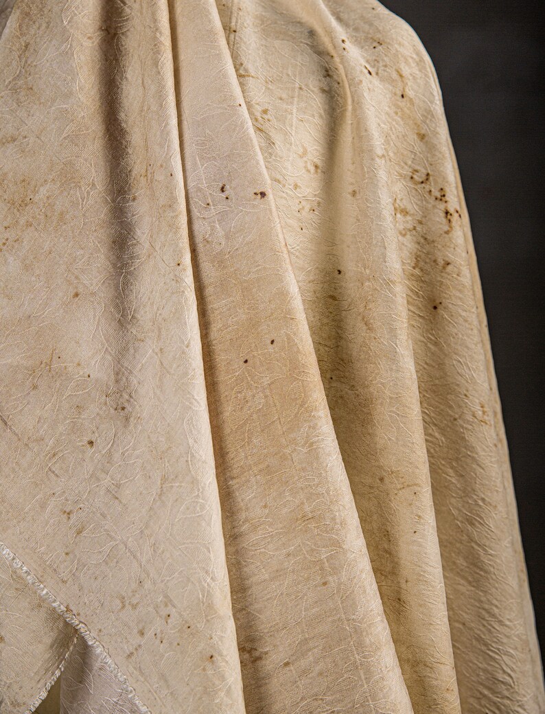 May include: A white fabric with a textured pattern and brown stains.