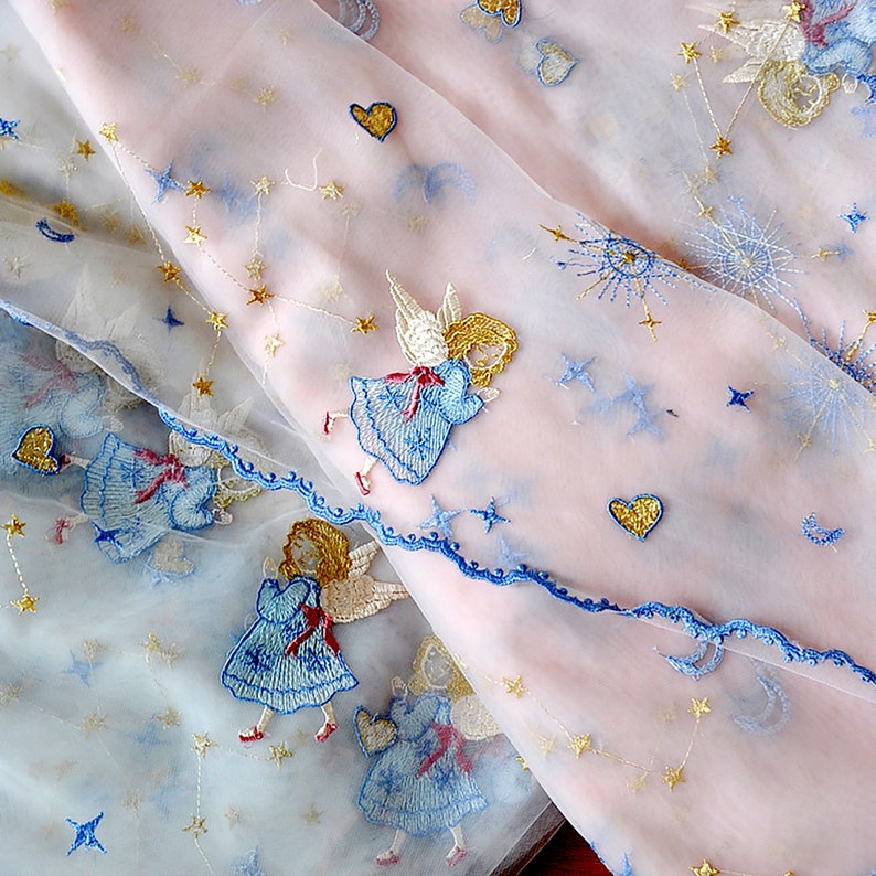 Puede incluir: Tela rosa transparente con bordados azules y dorados de &aacute;ngeles, estrellas y corazones. La tela es delicada y transl&uacute;cida.