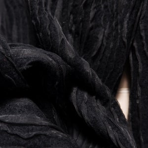 May include: Black fabric with a textured, crinkled, and wavy pattern. The fabric is soft and drapes well.