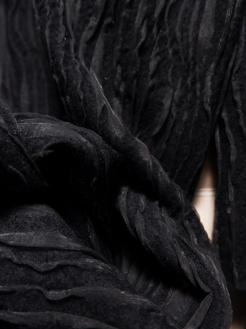 May include: Black fabric with a textured, crinkled, and wavy pattern. The fabric is soft and drapes well.