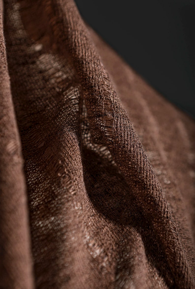 May include: Close-up of a brown fabric with a textured weave. The fabric is folded and has a slightly frayed edge.