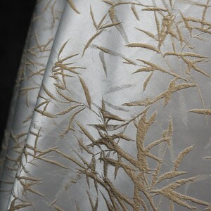 May include: White fabric with a raised embossed pattern of brown bamboo branches.