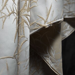 May include: Close-up of a white fabric with a raised, embossed pattern of beige bamboo leaves.
