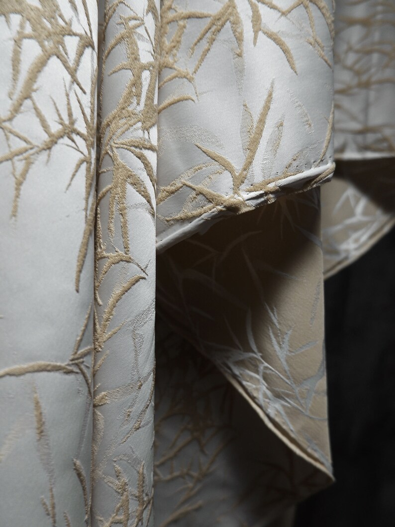 May include: Close-up of a white fabric with a raised, embossed pattern of beige bamboo leaves.