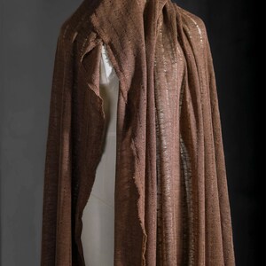 May include: A brown linen fabric draped over a mannequin. The fabric has a loose weave and a slightly textured surface.