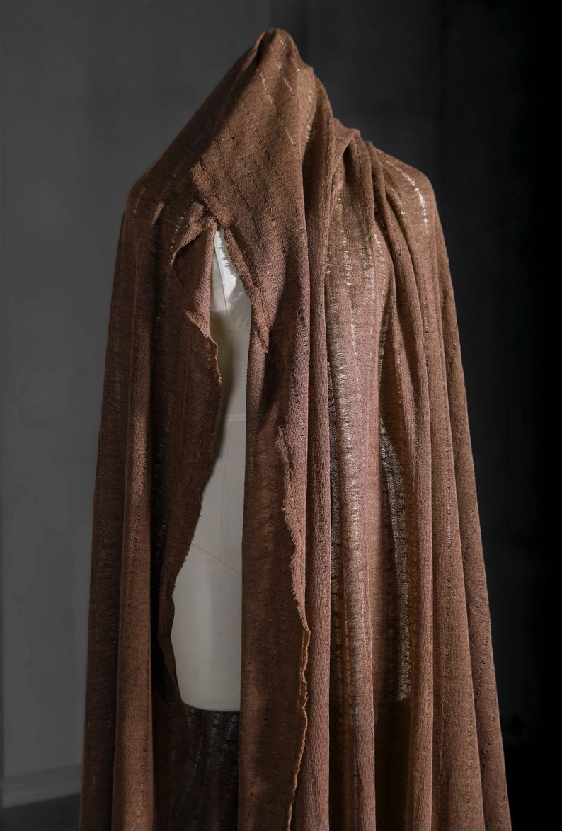 May include: A brown linen fabric draped over a mannequin. The fabric has a loose weave and a slightly textured surface.