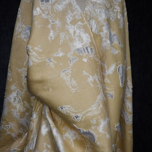 Puede incluir: Una tela beige con un patrón en relieve blanco. La tela tiene una superficie texturizada, casi rugosa.