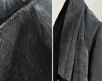 May include: Close-up of a black fabric with a textured, wavy pattern. The fabric is soft and has a subtle sheen.