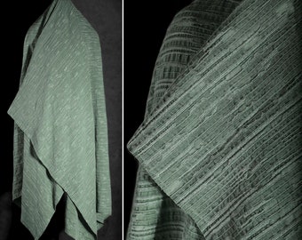 May include: A green textured fabric with a subtle striped pattern. The fabric is folded and draped over a surface.