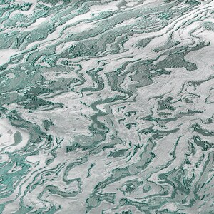 K&ouml;nnte beinhalten: Abstrakter Stoff in Teal und Silber mit einem strukturierten, wellenf&ouml;rmigen Muster.