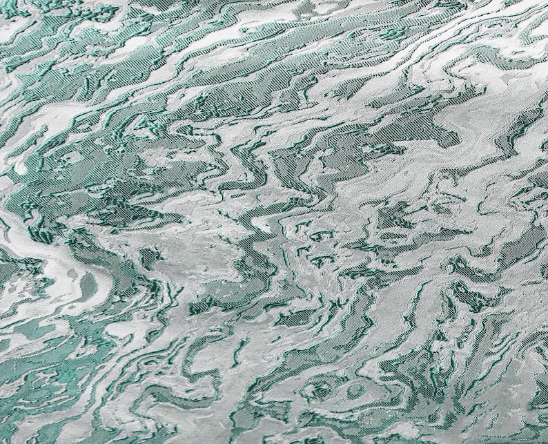 K&ouml;nnte beinhalten: Abstrakter Stoff in Teal und Silber mit einem strukturierten, wellenf&ouml;rmigen Muster.