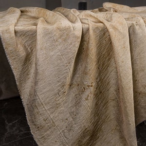May include: A beige fabric tablecloth with a subtle pattern and brown stains.
