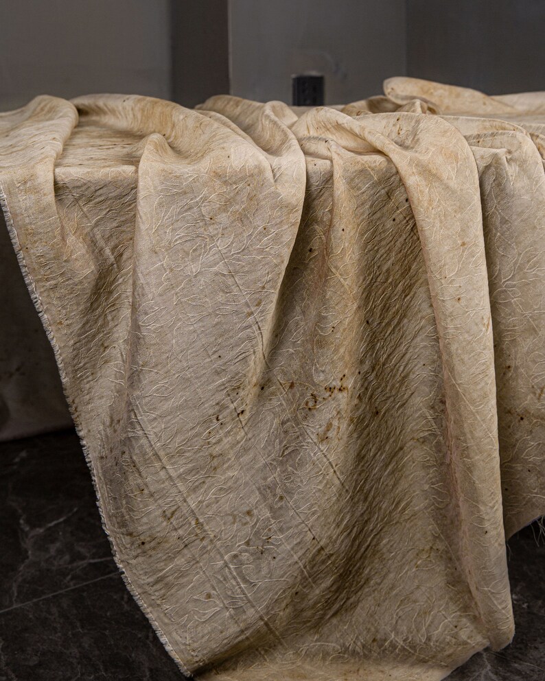 May include: A beige fabric tablecloth with a subtle pattern and brown stains.