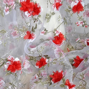 May include: White sheer fabric with a floral pattern featuring red 3D flowers. The fabric has a delicate, airy feel and is perfect for curtains, tablecloths, or other decorative purposes.