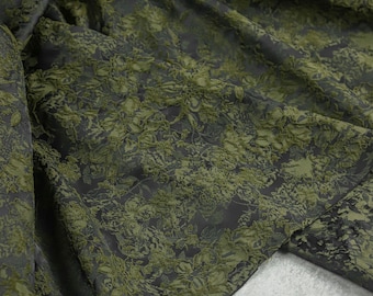 May include: Green fabric with a raised floral pattern. The fabric is textured and has a subtle sheen.