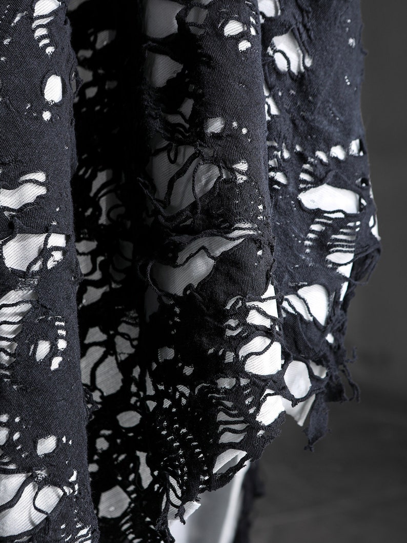 May include: Black fabric with a distressed, ripped, and frayed design. The fabric has a lace-like appearance with large holes throughout.