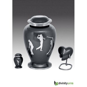 May include: A set of three black and silver golf-themed cremation urns. The largest urn is a traditional shape with a silver lid and a silver base. The medium urn is a heart shape with a silver base. The smallest urn is a traditional shape with a silver lid and base. All three urns feature a silver silhouette of a golfer.