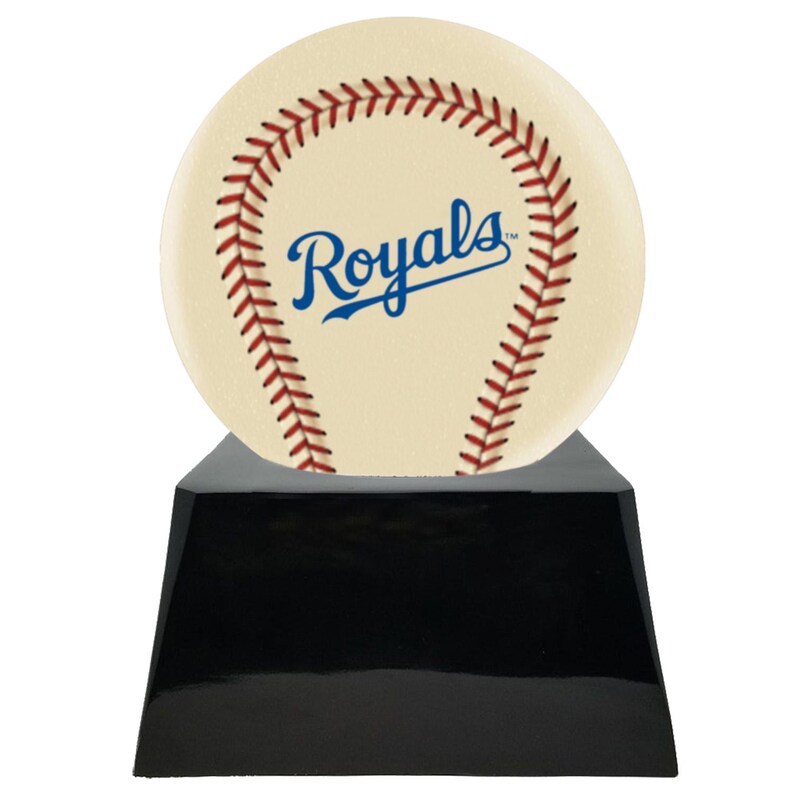Może przedstawiać: Trofeum o tematyce baseballowej z kremową piłką z czerwonymi szwami i napisem "Royals" w kolorze niebieskim. Piłka spoczywa na błyszczącej czarnej podstawie w kształcie trapezu. Nagroda sportowa.