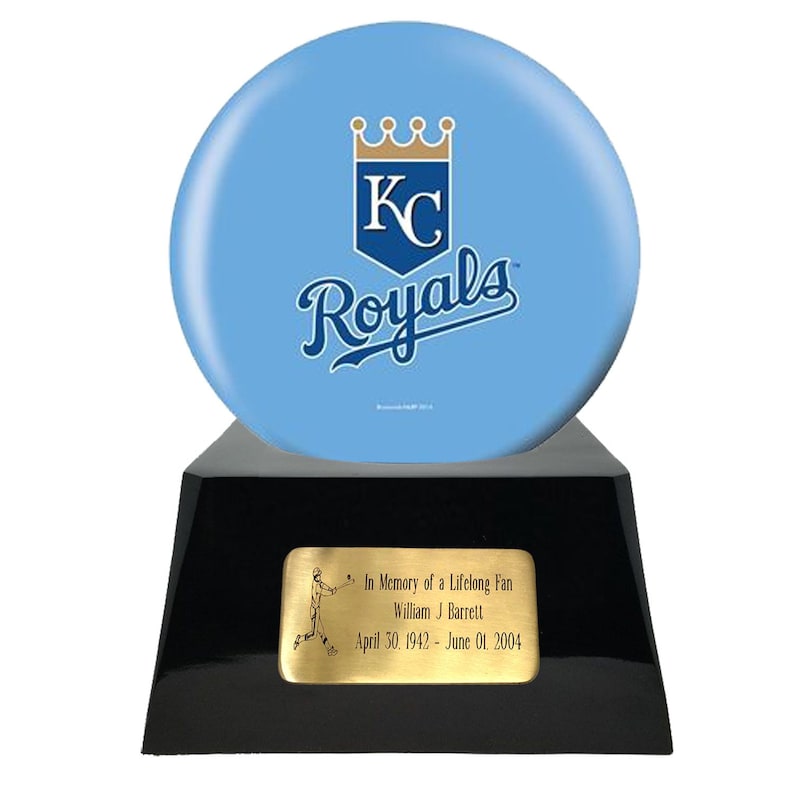 Op de afbeelding: Een herdenkingstrofee met een lichtblauwe honkbal met het Kansas City Royals-logo, gemonteerd op een zwarte basis. Een gouden plaatje leest "In Memory of a Lifelong Fan" met een naam en data.