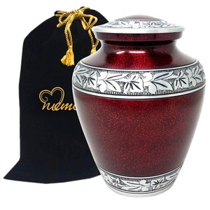 May include: Red and silver metal cremation urn with an engraved floral design. The urn comes with a black velvet bag.