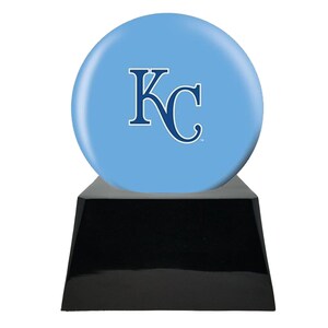 Op de afbeelding: Een lichtblauwe bol met een wit en blauw "KC" logo, gemonteerd op een zwarte, trapeziumvormige basis. De bol heeft een glanzende afwerking en de basis heeft een reflecterend oppervlak. Dit is een trofee of decoratief item.