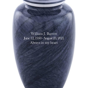 May include: A dark blue and grey marble-patterned cremation urn with a removable lid. The front is engraved with the text: William J. Barrett, June 12, 1950 - August 23, 2021, Always in my heart. The urn features a smooth, polished finish.