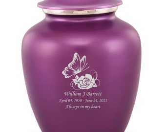May include: A purple metal cremation urn with a removable lid. The front features an engraved white graphic of a butterfly resting on a rose, followed by the text: William J Barrett, April 04, 1950 - June 24, 2021, Always in my heart.