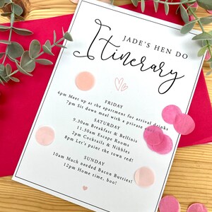 May include: A white card with a black title "Itinerary" and a pink heart design. The card lists a weekend itinerary for a hen party, including activities like breakfast, escape rooms, and painting the town red.