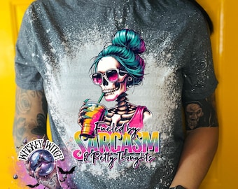 May include: A gray t-shirt with a bleach-splattered design featuring a skeleton with blue hair holding a colorful drink. The text "Fueled by Sarcasm & Petty Thoughts" is printed on the shirt.