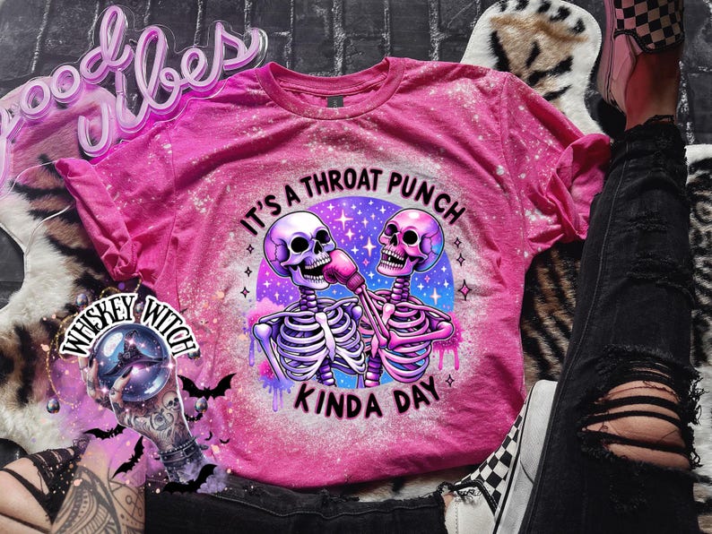 May include: Pink t-shirt with a bleached effect featuring two skeletons wearing boxing gloves and the text "It's a throat punch kinda day".