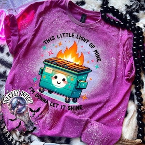 Berry Pink t-shirt with a bleach-splattered design featuring a cartoon dumpster on fire with the text "This little light of mine I'm gonna let it shine".