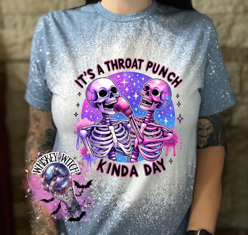May include: A blue bleached t-shirt with a graphic of two skeletons wearing boxing gloves and the text "It's a throat punch kinda day".