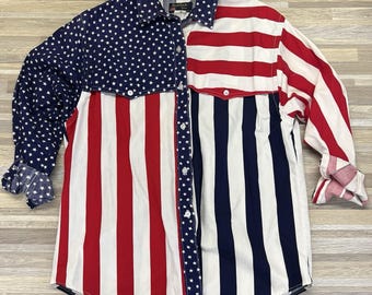 May include: A long-sleeved button-down shirt with a patriotic design. The shirt features a patchwork design with the American flag. The left side has a navy blue sleeve with white stars, and the right side has red and white stripes.