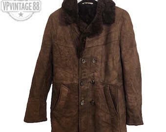 May include: A brown vintage leather coat with a shearling collar and lining. The double-breasted coat has two front pockets and button closures. The coat is hanging on a white hanger.