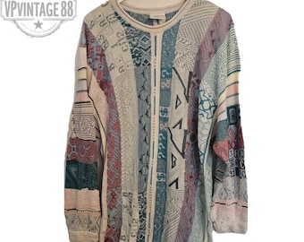 Könnte beinhalten: Ein Vintage-Pullover in vielen Farben mit einem Patchwork-Design. Der Pullover weist eine Vielzahl von Mustern und Texturen in Beige-, Türkis-, Rosa- und Lilatönen auf. Der Pullover wird auf einem weißen Kleiderbügel präsentiert.