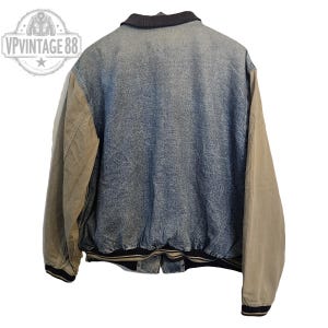 Pu&ograve; includere: Giacca di jeans vintage con maniche color cachi e colletto nero. La giacca ha un corpo in denim blu sbiadito e un orlo a righe bianche e nere. Le maniche sono di colore cachi pieno. La giacca &egrave; un classico stile bomber.