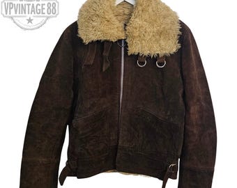 May include: A brown suede jacket with a tan faux fur collar. The jacket has a zipper closure, two front pockets, and adjustable cuffs. The jacket has a vintage look and feel. The logo "VP Vintage 88" is in the upper left corner.