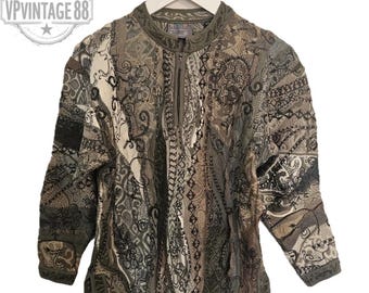 Könnte beinhalten: Ein olivgrüner Vintage-Pullover mit halbem Reißverschluss und aufwendigem Muster. Der Pullover hat einen hohen Kragen und lange Ärmel. Das Design umfasst Paisley- und geometrische Muster in Grün-, Braun- und Cremetönen. Das Etikett lautet "VP Vintage 88".