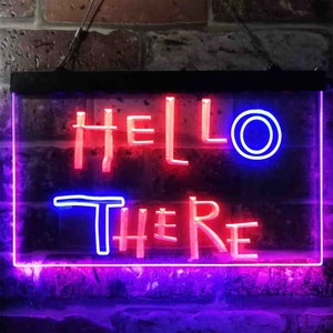Puede incluir: Letrero luminoso rectangular con las palabras "HELLO THERE" en neón rojo y azul. El letrero está colgado contra una pared de ladrillos. Las letras de neón están delineadas en azul y rojo.