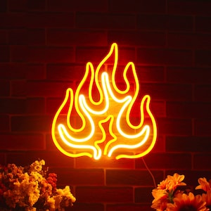 May include: A neon sign shaped like flames, glowing bright yellow. It's mounted on a red brick wall. The scene includes flowers in the foreground. The neon sign is a decorative item.