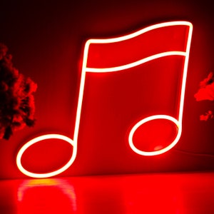 Può includere: Una luce al neon rossa a forma di nota musicale. La luce al neon è brillante e brilla su uno sfondo rosso. La nota musicale ha una parte superiore curva e due sezioni inferiori arrotondate.