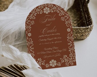 May include: A brown arch-shaped wedding invitation with a floral design. The invitation reads "Frida and Carlos joyfully invite you to their wedding Saturday August 19th 20xx at 3 o'clock in the afternoon Wedding Palace 111 Main Drive, San Diego, CA Reception to Follow"