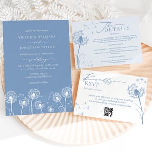 May include: Wedding stationery set in blue and white, with dandelion designs. The invitation card displays the names Victoria Williams and Jonathan Taylor, the wedding date, and venue. RSVP and details cards are also included in the set.