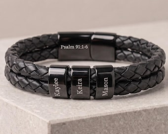 May include: A black braided leather bracelet featuring a polished black metal clasp engraved with the text Psalm 91:1-6 and three movable black metal beads engraved with the names Kaylee, Keira, and Mason in a clean, sans-serif font.