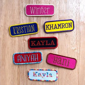 May include: Seven colorful embroidered name tags with different names, including "Winter", "Kristian", "Khamon", "Kayla", "Aniyah", "yani", and "Kayla".