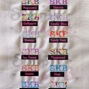 May include: A thread color chart featuring the letters SKB embroidered in twelve distinct color combinations. Each sample is labeled with names like Hopscotch, Unicorn, Dollhouse, Vanilla Bliss, Dreams, Candy Corn, Ice Cream, Playground, Sherbet, Skye, Cotton Candy, and Multi.